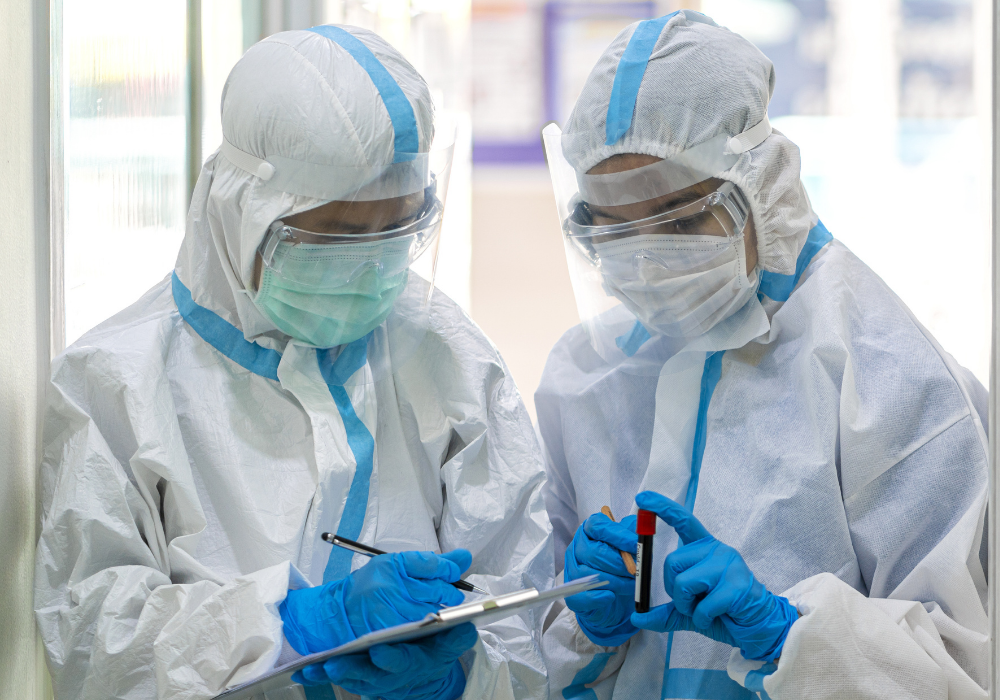 two doctors in full PPE with a vial of blood