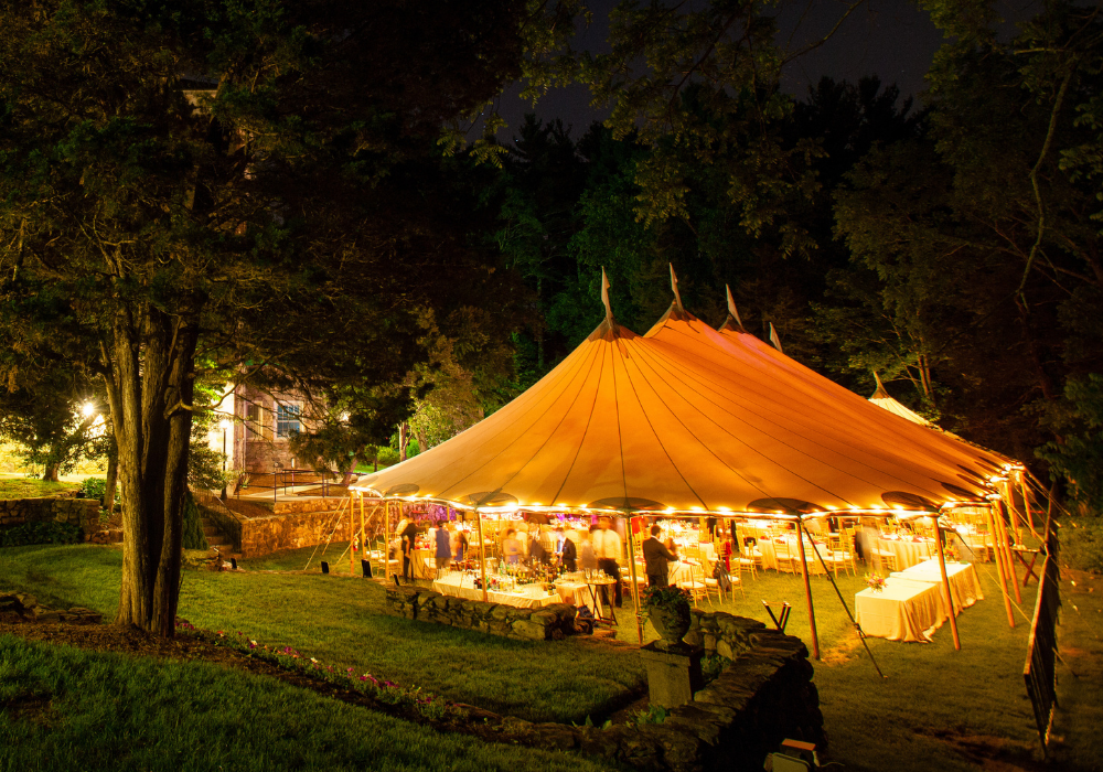 marquee lit up at night for an event among trees