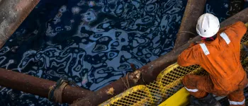 oil rig worker in orange PPE looking into the sea